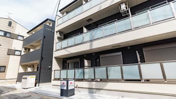 A multi-story building with balconies, a trash bin, and a sign for 'En Osaka.'
