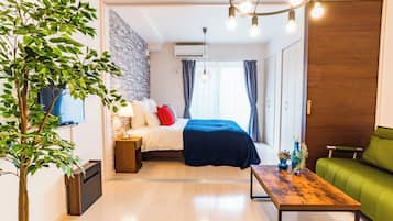 A modern room with a bed, a green sofa, a wooden coffee table, and a potted plant.