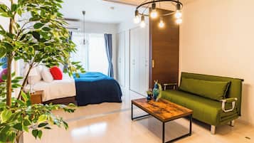 Una habitación moderna con una cama, un sofá verde, una mesa de centro de madera y una planta.