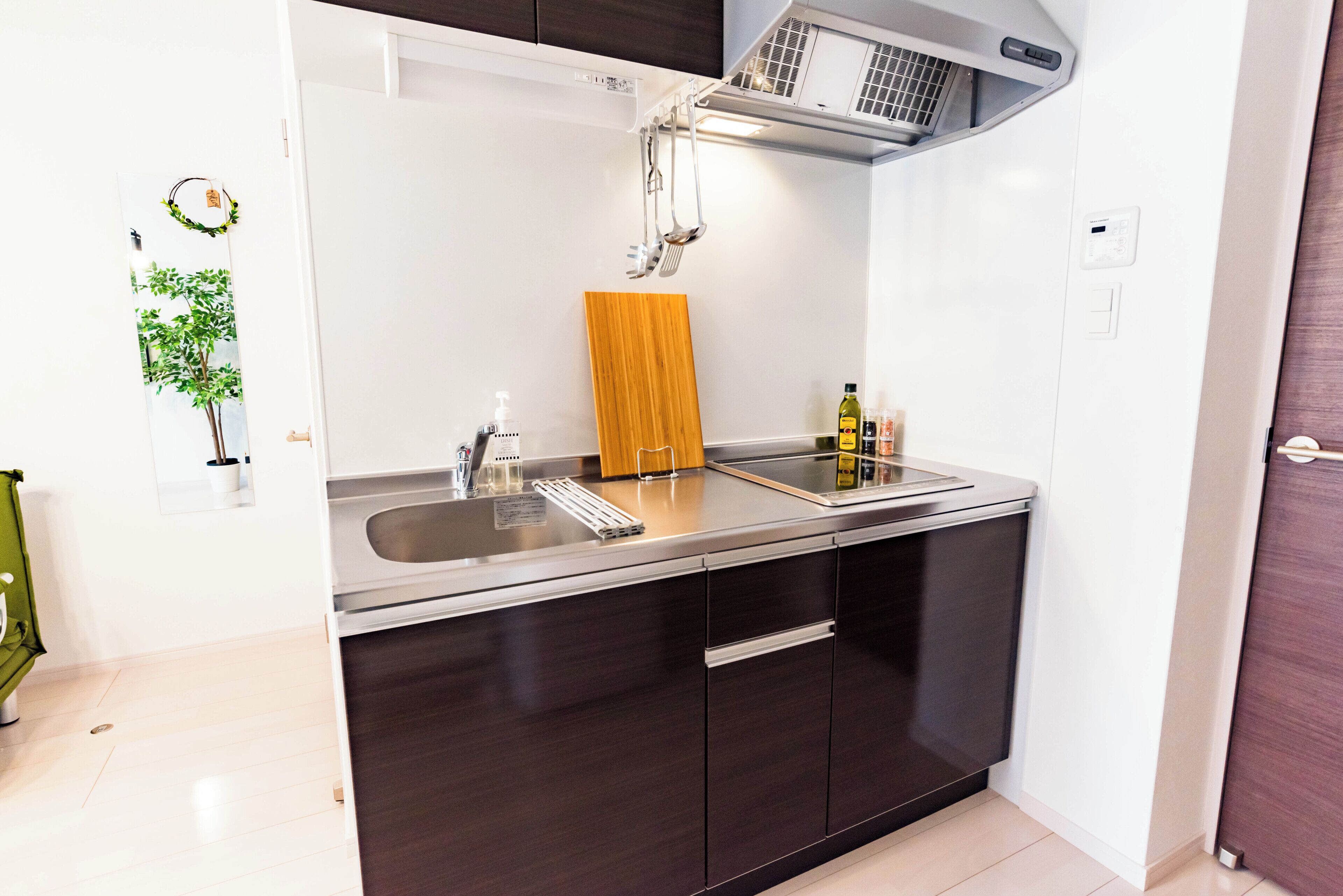 Una cocina moderna con horno integrado, un lavamanos de acero inoxidable y una encimera de madera.
