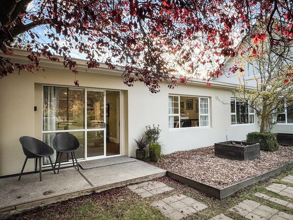 Uma casa moderna com um pátio, porta de correr e um pequeno jardim.