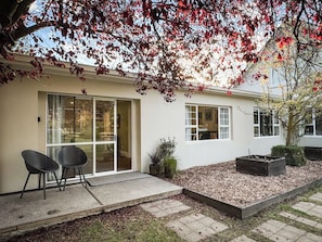 Une maison moderne dotée d’un patio, d’une porte-fenêtre coulissante et d’un petit jardin.
