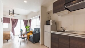 A modern kitchen with a microwave, refrigerator, and sink. There is a dining area with a table and chairs, and a sofa.