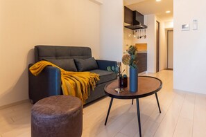 A modern living room with a sofa, ottoman, and a coffee table. - FDS NEXUS (OSAKA/NISHINARIKU/TENGACHAYA)