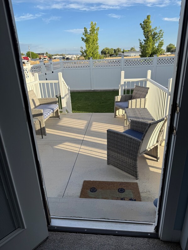 An outdoor patio with wicker furniture and a white fence.