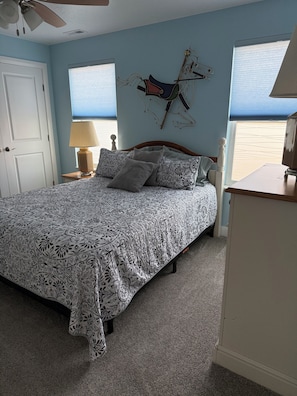 Een slaapkamer met een bed, een nachtkastje, een lamp, een dressoir en een wanddecoratie.