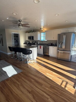A modern kitchen with white cabinets, stainless steel appliances, and a wooden floor.