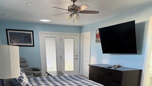 Een slaapkamer met een bed, een plafondventilator, een televisie en een dressoir.