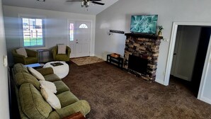 Un salon doté d’une cheminée, d’un ventilateur de plafond et d’un téléviseur fixé au mur, au-dessus de la cheminée.