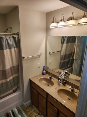 Une salle de bain avec une baignoire, un meuble-lavabo avec deux vasques, un miroir et un porte-serviettes.