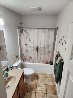 Un baño con cortina de ducha con diseño de libélula, inodoro, lavabo y bañera.