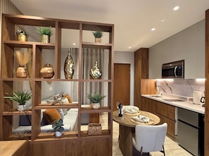A modern kitchen with a wooden partition, built-in appliances, and a dining area with a round table and chairs. - Stylish & Luxurious Stay in the Heart of Playa del Carmen (Playa del Carmen)