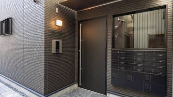 A modern building facade with a brick wall, a door, and a large mailbox with numbered mail slots.