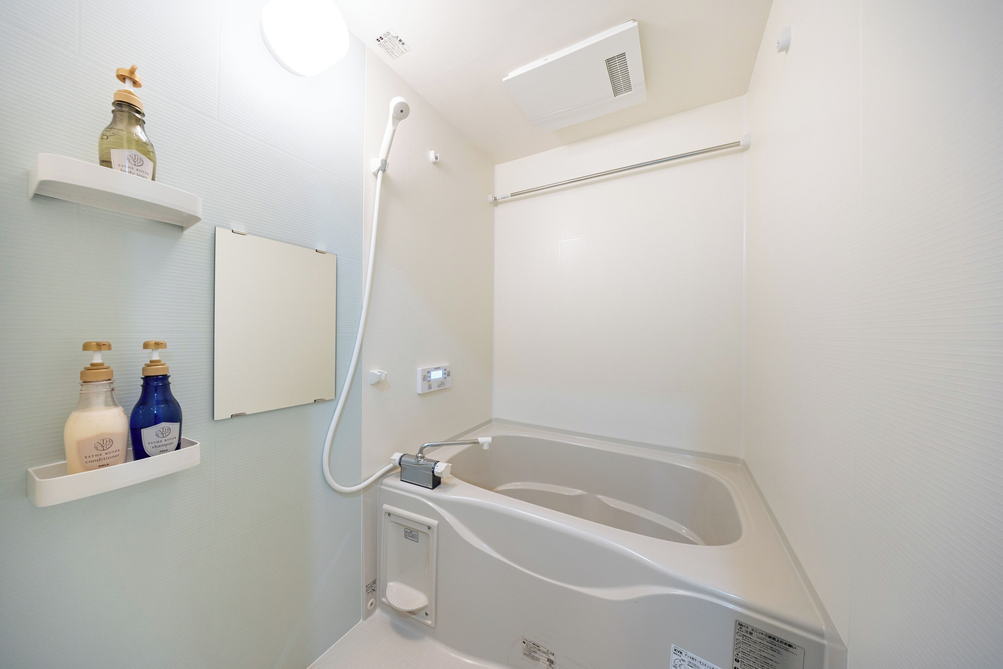 Une salle de bain avec une baignoire, une douche et deux étagères remplies de bouteilles.