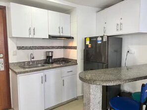 A kitchen with white cabinets, a gas stove, a coffee maker, a refrigerator, and a granite countertop. - 17th Floor, Ocean View (Cartagena de Indias)