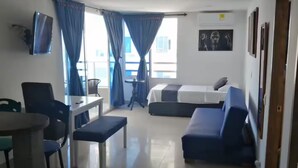Ein Hotelzimmer mit Bett, Schreibtisch, Stuhl, Fernseher und einem Fenster mit Vorhängen.