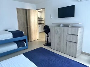 A bedroom with a bed, a blue mattress, a wooden wardrobe, a standing fan, and a TV on the wall. - 17th Floor, Ocean View (Cartagena de Indias)