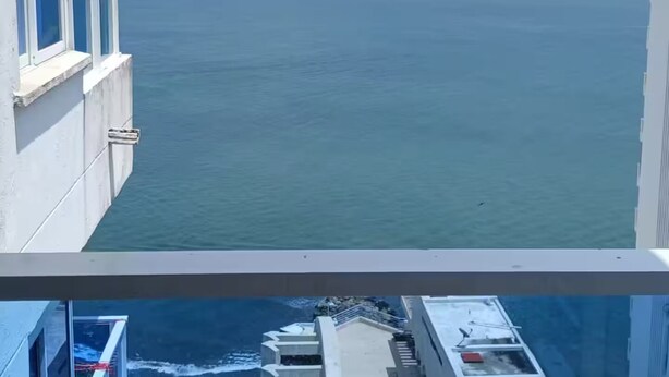Ein Hochhaus mit Blick auf das Meer und Hügel in der Ferne.