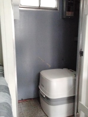 A small, enclosed bathroom with a toilet and a window.