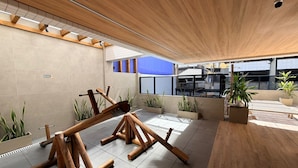 An outdoor area with a wooden structure, tiled flooring, and potted plants. - Edifício HIGH (Maceió)
