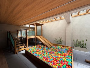 Ein Spielbereich mit Ballgrube, Holzspielgeräten und einer Treppe.