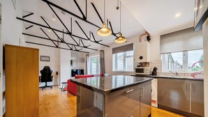 Eine moderne Küche mit Edelstahlgeräten, Holzboden und einer Essecke mit einem roten Sofa.