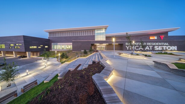 Un edificio moderno con techo plano, ventanas grandes y un cartel que dice 'Brookfield Residential YMCA at Seton'.
