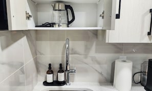 A bathroom with a sink, a coffee maker, and two bottles of soap. - Modern Suite in Seton - King Bed, 85" TV, Near South Health Campus & YMCA (Calgary)