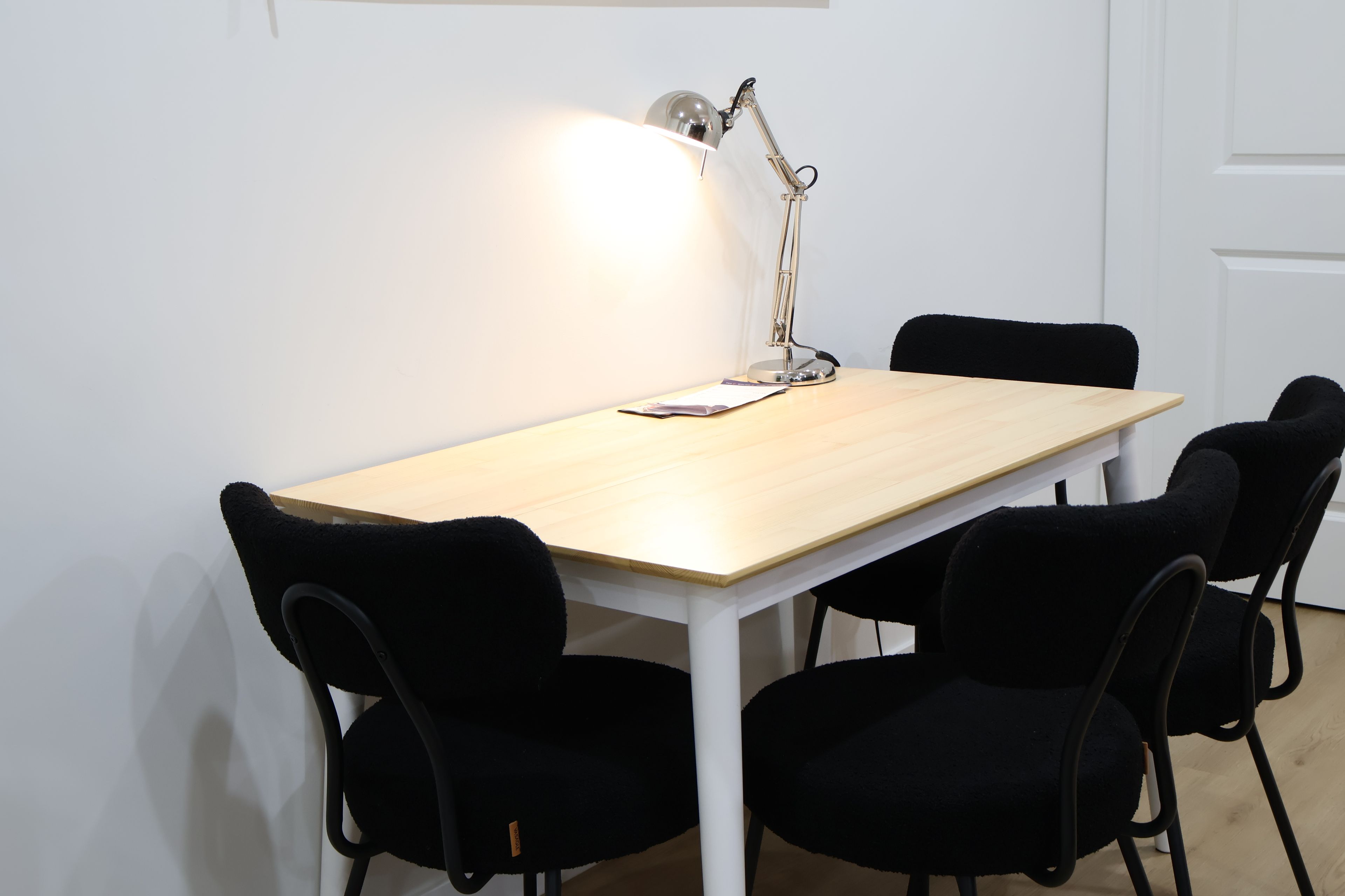 Un espace repas simple et moderne, avec une table en bois et des chaises noires.