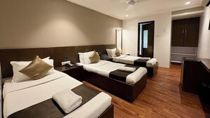 Une chambre d’hôtel avec deux lits, un bureau, un miroir et une armoire.