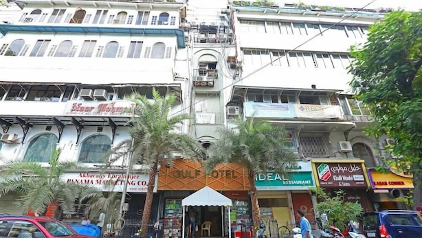 Un hôtel avec une entrée principale, une enseigne et un petit auvent.