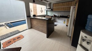 A modern kitchen with a central island, wooden cabinets, a built-in sink, and a water dispenser. - Cozy rooms for rent (Belém)