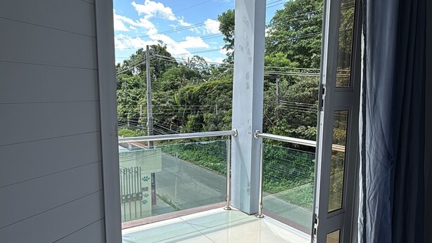 A room with a sliding glass door leading to a balcony with a metal railing and a view of greenery. - Cozy rooms for rent (Belém)