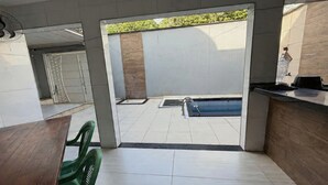 A modern interior with a pool area visible through a glass door, a reception desk, and a dining area with chairs. - Cozy rooms for rent (Belém)