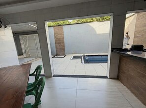 A modern interior with a pool area visible through a glass door, a reception desk, and a dining area with chairs. - Cozy rooms for rent (Belém)