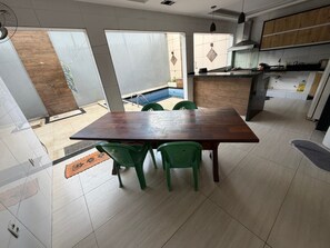 A modern kitchen with a dining area, large windows, and a view of a swimming pool. - Cozy rooms for rent (Belém)