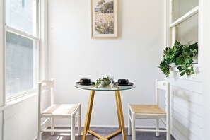 A corner room with a glass table, two white chairs, a small plant, and a painting on the wall. - 3BR Passaic Home Near NY/NJ Stadium, NYC Access, Sleeps 6 (Passaic)
