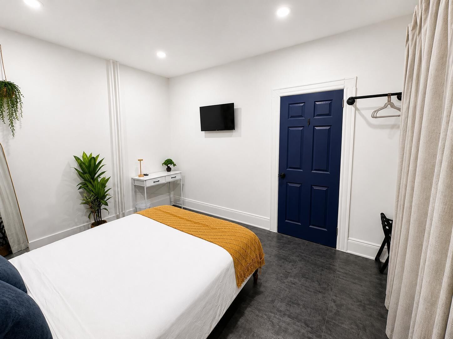 A hotel room with a bed, a desk, a TV, a wardrobe, and a door.