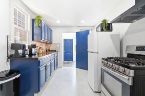 A kitchen with blue cabinets, a stove, a refrigerator, and a coffee machine. - 3BR Passaic Home Near NY/NJ Stadium, NYC Access, Sleeps 6 (Passaic)