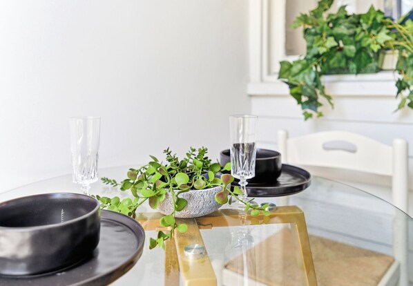 A dining table with two clear glasses, a bowl, and a small plant.