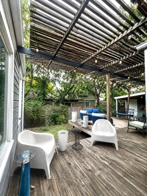 Eine Terrasse im Freien mit Holzdeck, weißen Möbeln und einer Pergola mit Lichterketten.