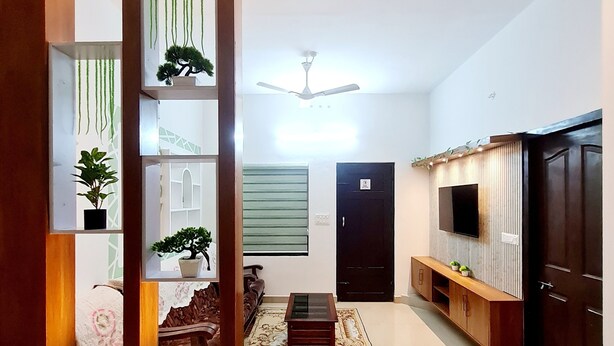 Un vaste espace de vie agrémenté d’un ventilateur de plafond, d’un téléviseur fixé au mur, d’un meuble en bois foncé et d’un tapis à motifs.