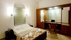 Une chambre à coucher comprenant un lit, un bureau, une chaise, un ventilateur de plafond, un miroir et une table de chevet.