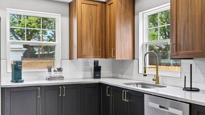 A kitchen with dark cabinets, a white countertop, a sink, and a coffee maker. - Fully Updated Field Club Colonial - 4BR Near UNMC & Blackstone (Omaha)