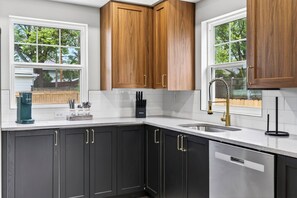A kitchen with dark cabinets, a white countertop, a sink, and a coffee maker. - Fully Updated Field Club Colonial - 4BR Near UNMC & Blackstone (Omaha)