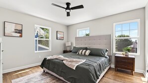 A bedroom with a bed, a ceiling fan, two windows, a nightstand, and a rug. - Fully Updated Field Club Colonial - 4BR Near UNMC & Blackstone (Omaha)