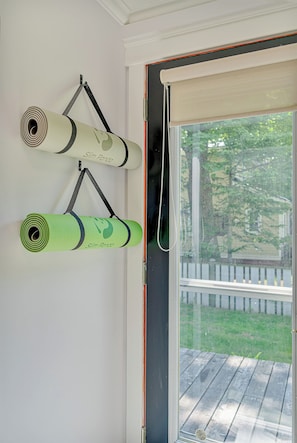 Eine Yogamatze hängt an einer Wand mit Blick auf eine Holzterrasse und einen weißen Zaun.