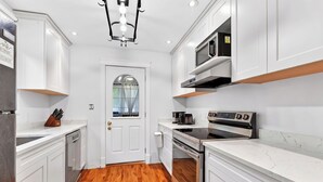A modern kitchen with white cabinetry, a built-in oven, and a microwave. - Elevated French‑country coastal charm in the heart of Charlottetown (Charlottetown)