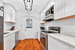 A modern kitchen with white cabinetry, a built-in oven, and a microwave.