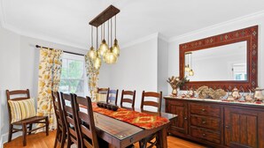 A dining room with a wooden table, chairs, a chandelier, and a large mirror. - Elevated French‑country coastal charm in the heart of Charlottetown (Charlottetown)